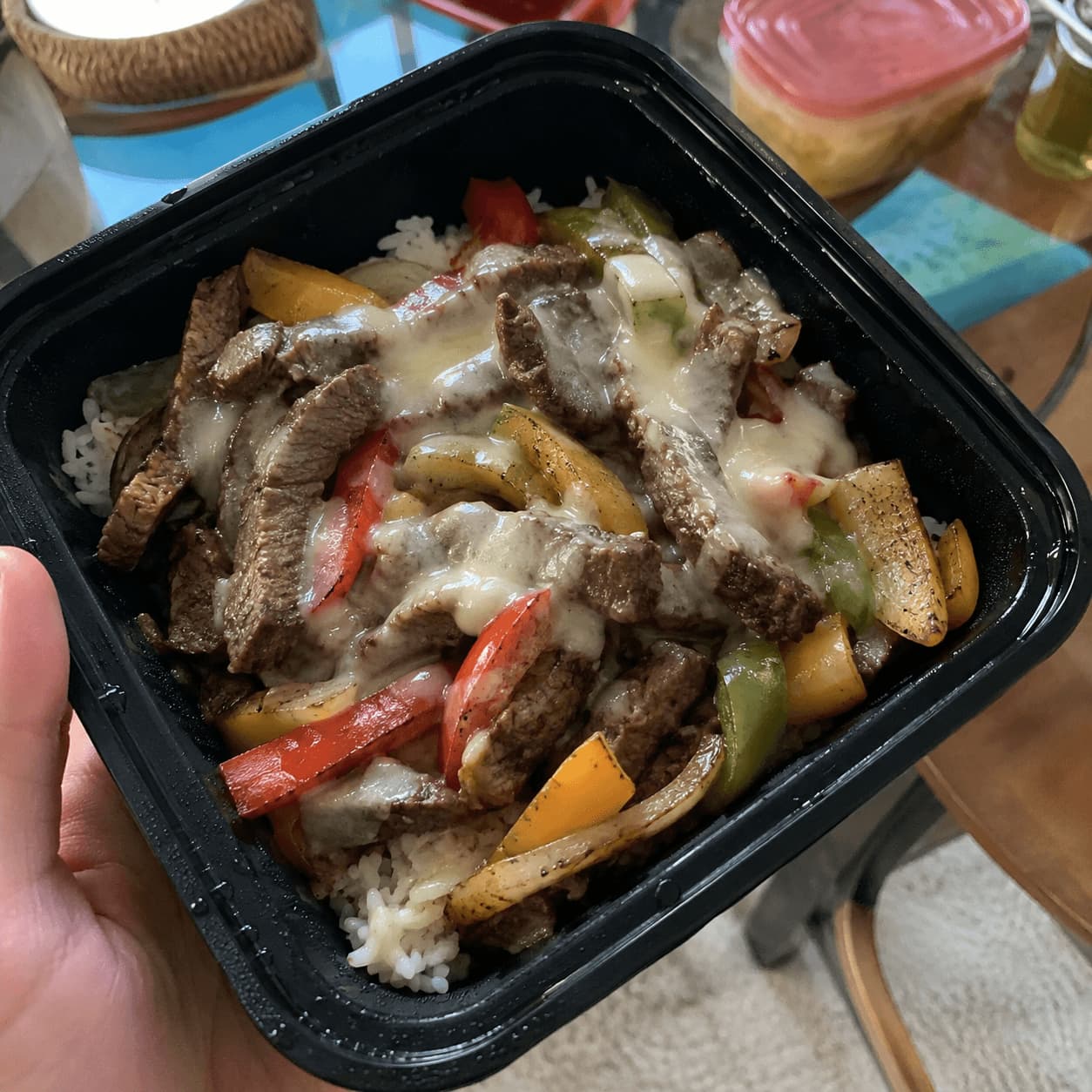 Meal prep container of Philly cheesesteak with steak, peppers, and melted provolone